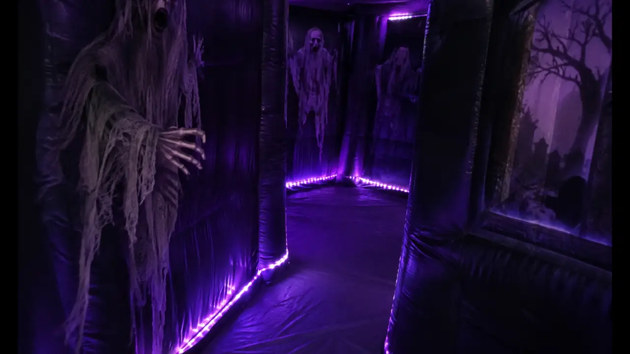 Dunkles aufblasbares Gruselhaus-Labyrinth mit lila LED-Beleuchtung im Inneren